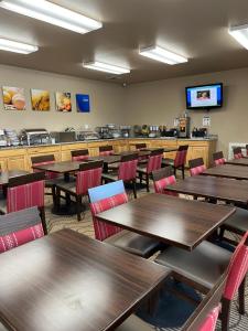Comfort Inn & Suites Ocean Shores في أوشن شورز: غرفة طعام مع طاولات خشبية وكراسي حمراء