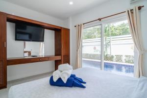 sypialnia z telewizorem i łóżkiem z ręcznikami w obiekcie Jasmine Pool Villa in Nai Harn w mieście Rawai Beach