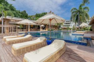 une piscine avec chaises en osier et parasols dans l'établissement Poppy Beachfront Residence, à Rawai Beach