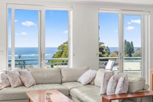 uma sala de estar com um sofá e vistas para o oceano em AeA The Coogee View em Sidney