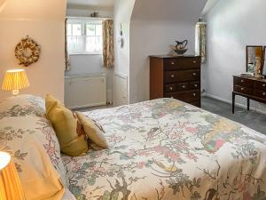a bedroom with a bed with a floral bedspread at Granary Cottage in Torquay