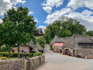 a village with thatched roofs and a fence at Granary Cottage in Torquay