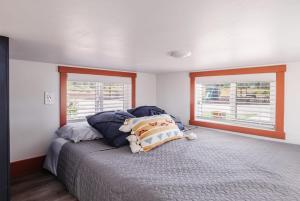 a bedroom with a bed with pillows and two windows at New calm & relaxing Tiny House w deck near ZION in Apple Valley