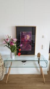 un tavolo in vetro con un vaso di fiori e una TV di Luxury, Spacious, Sunny home in the heart of Berlin a Berlino
