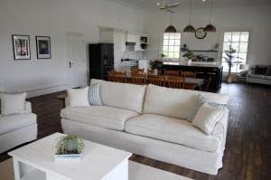a living room with a white couch and a kitchen at Yallingup Homestead Guest House in Dunsborough