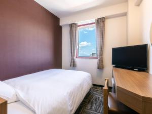um quarto de hotel com uma cama e uma televisão de ecrã plano em Hotel Wing International Sukagawa em Sukagawa
