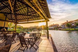 a patio with tables and chairs next to a river at Golf Ville Resort Residence Bloco 64mar Apto 31 Aquiraz - Ceara - Brasil in Aquiraz