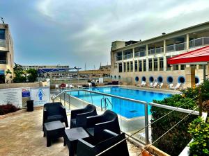 a swimming pool with chairs and a building at Charming apartment with sea view at Marina Village Herzliya in Herzliyya B