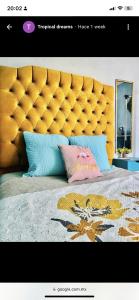 1 cama grande con cabecero amarillo y almohadas en Tropical Dreams en Villahermosa