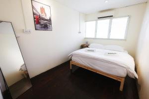 una camera da letto con un letto con lenzuola bianche e una finestra di monstera guesthouse (Lenggong) a Kampong Ulu Jepai