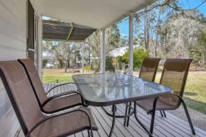 una mesa de cristal y sillas en un porche en Tabitha Hill Estate close to wineries and nature, en Bellbird