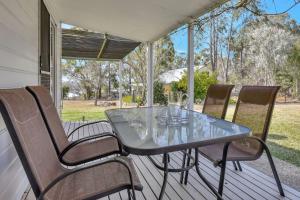 a glass table and chairs on a porch at Tabitha Hill Estate close to wineries and nature in Bellbird