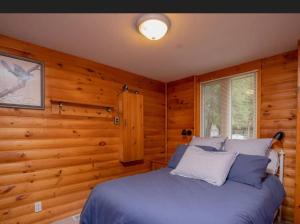 1 dormitorio con 1 cama azul en una habitación de madera en Lovely waterfront private cottage with hot tube, en Head Lake