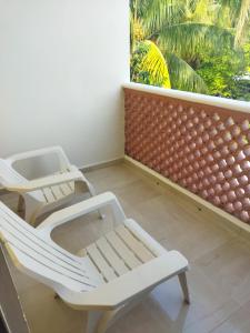 - deux chaises blanches assises sur un balcon avec fenêtre dans l'établissement Hotel Beach Don Gonzalo, à Celestún