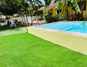 a swimming pool with green grass next to a house at Bon Bini Kokolishi in Willemstad
