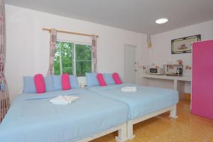 a bedroom with two beds with blue and pink pillows at เขาค้อออฟเลิฟ in Khao Kho