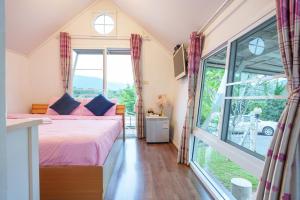 ein Schlafzimmer mit einem Bett und einem großen Fenster in der Unterkunft เขาค้อออฟเลิฟ in Khao Kho