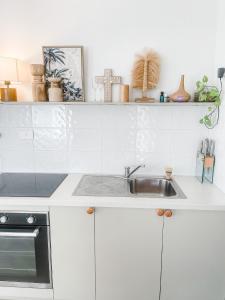 a kitchen with white cabinets and a sink at Beach Bungalow Yeppoon in Yeppoon