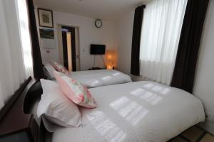 two beds in a hotel room with at 東京昭島迎賓館a in Akishima