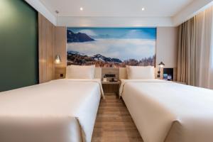 two beds in a hotel room with a painting on the wall at Atour Hotel Lanzhou Xiguan Zhengning Road in Lanzhou