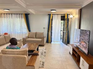 a young boy sitting in a living room watching tv at Elena & Kimberly in Gulu