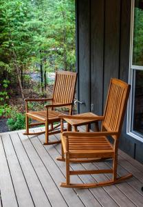 - deux chaises en bois assises sur la terrasse couverte d'une maison dans l'établissement Backwoods Cabins, à Carson