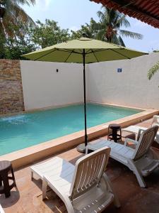 a pair of chairs and an umbrella next to a swimming pool at Hotel Beach Don Gonzalo in Celestún