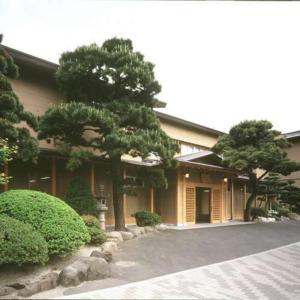 budynek z dwoma drzewami przed nim w obiekcie Ryokan Ichinomatsu w mieście Hakodate
