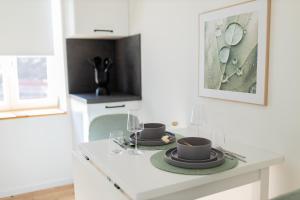 a white kitchen with two plates and glasses on a counter at DWELLSTAY - Zuse Höfe Bad Hersfeld in Bad Hersfeld