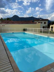 Una gran piscina en un hotel con agua azul. en Casa de Praia Martins De Sá Condomínio Caraguatatuba, en Caraguatatuba