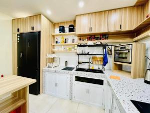 eine Küche mit weißen Schränken und einem schwarzen Kühlschrank in der Unterkunft Ule Home in Ho-Chi-Minh-Stadt