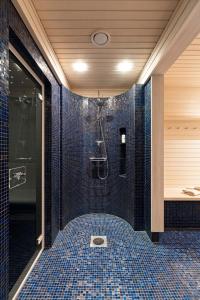 un bagno con doccia con piastrelle blu di Villa Rukatunturi a Kuusamo