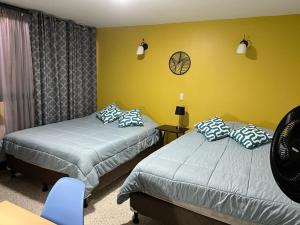 a bedroom with two beds and a yellow wall at Corazón Sabana in San José