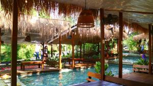 a resort with a swimming pool with straw umbrellas at Uma Villa Manado in Manado