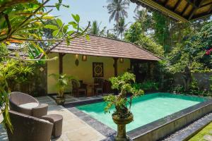 a swimming pool in a garden with a house at Dewata ubud in Ubud