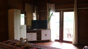 een woonkamer met een tv en een kamer met een bed bij Uma Villa Manado in Manado