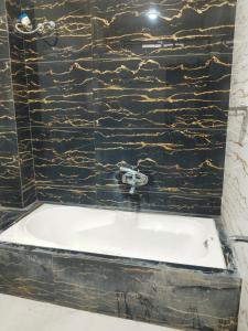 a bath tub in a bathroom with a black stone wall at Saanidhya home stay in Ujjain +22 photos