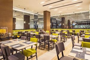 a restaurant with tables and chairs and yellow chairs at Belmont Hotel Manila in Manila