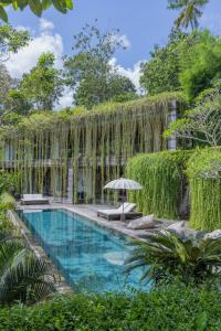 una piscina en un jardín con plantas colgantes en Chameleon Villa Bali en Tabanan