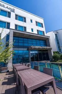 a hotel with tables and chairs in front of a building at Hotel The Grang Jungmun in Seogwipo