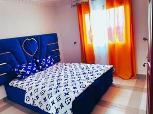 1 dormitorio con 1 cama con cortinas azules y naranjas en Makeena Berry Cosy Mboa --, en Douala