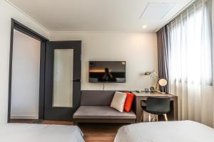 ソギポにあるHotel The Grang Jungmunのベッド、デスク、椅子が備わるホテルルームです。
