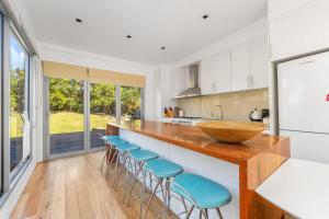 eine Küche mit einer Theke mit blauen Hockern in der Unterkunft Orions Lookout Vincentia in Vincentia