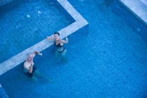 Dwóch mężczyzn pływa w basenie. w obiekcie Hotel Aikawa w mieście Sauraha
