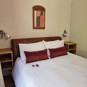 a white bed with two red pillows on it at House of House Guest House in Stellenbosch