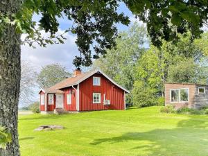 een rood huis op een groen veld met een boom bij Holiday home GÖTENE II in Götene