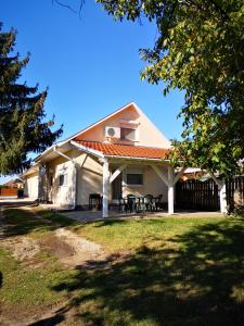 Casa blanca con porche con mesas de picnic en Kiss Apartman, en Balatonboglár