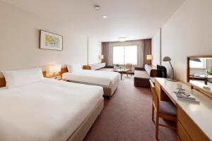 Habitación de hotel con cama grande y escritorio. en Manza Prince Hotel, en Tsumagoi