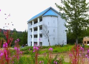 a white building with a blue roof in a field of flowers at 2nd Floor Newly Renovated room in Hatcher Pass Castle in Willow