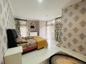 a bedroom with a bed and a window with curtains at Villa Benny Gsp Cipanas in Cibadak